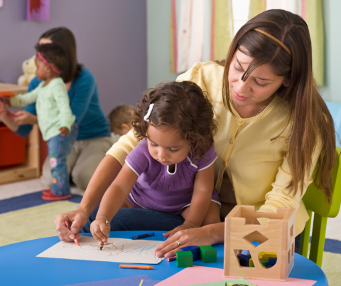 A little girl draws at a daycare.